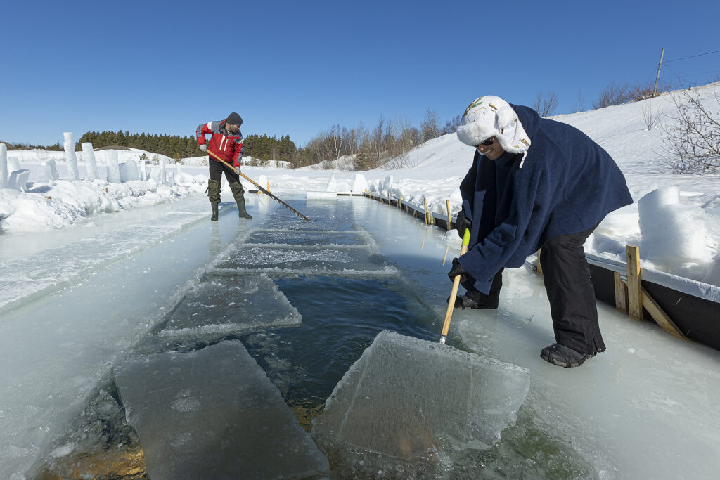 Martin Brunet uses an ice saw as Ricardo Pan Neves pulls the ice from a lake before ice swimmer go for a dip in the cold water